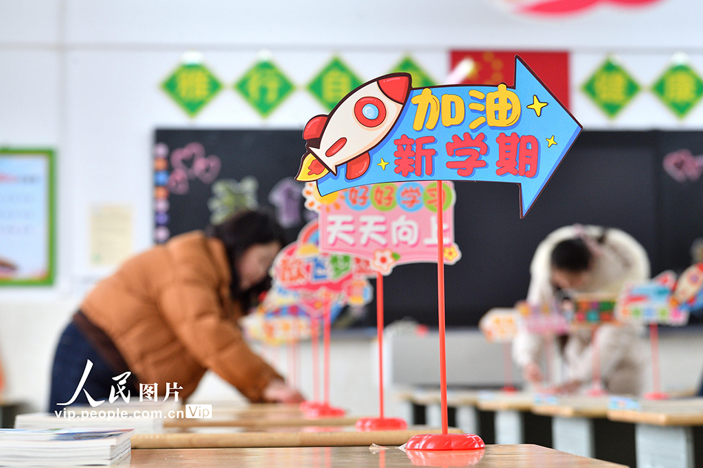 2026年3月2日,在湖北襄阳保康县实验小学,教师正在整理学生课桌上的新教材,认真做好开学前的各项准备工作。杨韬摄(人民图片网)