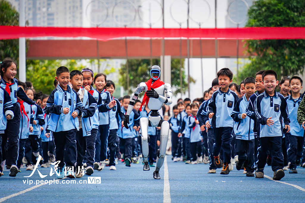 2026年3月2日,广西南宁天桃实验学校青运校区开展“开学第一跑”活动,学生们与人形机器人在操场上快乐奔跑,在互动体验中激发了对科学的探索兴趣。叶子榕摄(人民图片网)