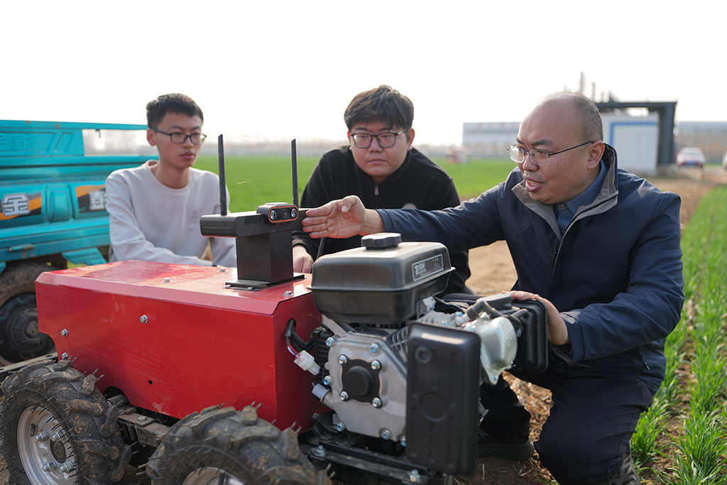 3月9日，山东农业大学副教授陈国庆（右）和团队成员在调试农田作业通用机器人。